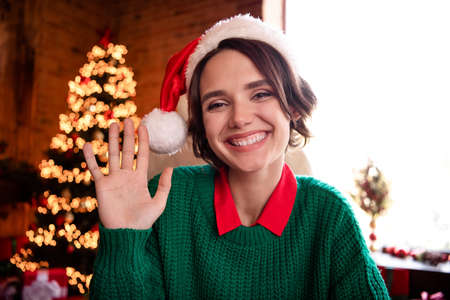 Photo of nice young brunette lady wave wear cap green sweater at home on holidayの写真素材