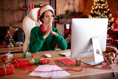 Photo of cute magic brunette lady work on pc wear cap green sweater in comfy appartmentの写真素材