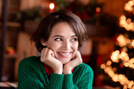Photo of adorable sweet young woman dressed knitted sweater arms cheeks smiling indoors room home...