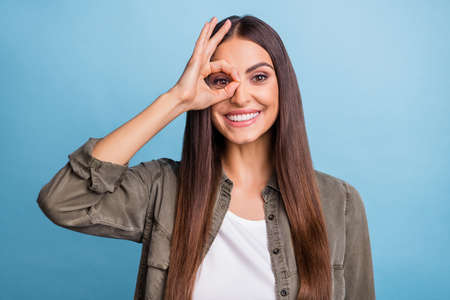 Photo portrait brunette woman smiling showing okay sign looking inside isolated pastel blue color...