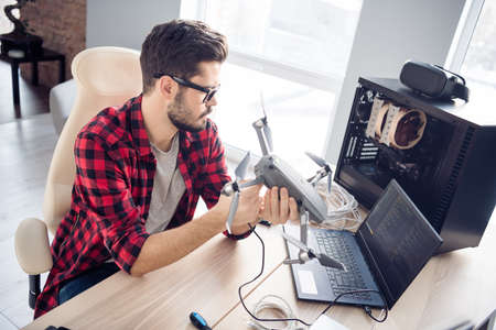 Portrait of attractive clever smart focused guy fixing drone bug software programming code security...