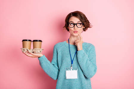 Photo of nice unsure curly brunette hairdo lady hold coffee look empty space wear spectacles blue sweater isolated on pink color backgroundの写真素材