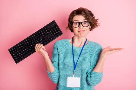Photo of sad curly brunette hairdo lady hold keyboard wear spectacles blue sweater isolated on pink...