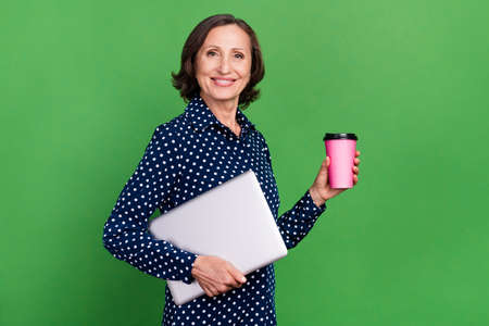 Profile photo of cute old manager lady hold laptop coffee wear dotted shirt isolated on green color backgroundの写真素材