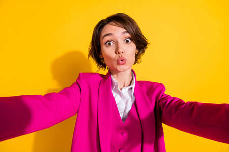 Photo of pretty impressed young woman dressed pink suit recording self video isolated yellow color backgroundの写真素材