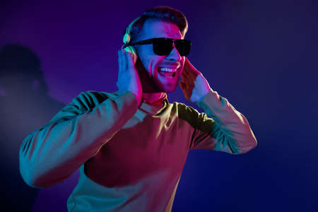 Photo portrait of man wearing sunglass listening music earphones overjoyed isolated dark purple color backgroundの写真素材