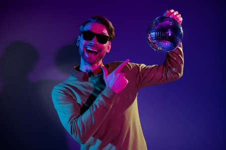 Photo portrait of man smiling in sunglass pointing finger disco ball music isolated purple color backgroundの写真素材