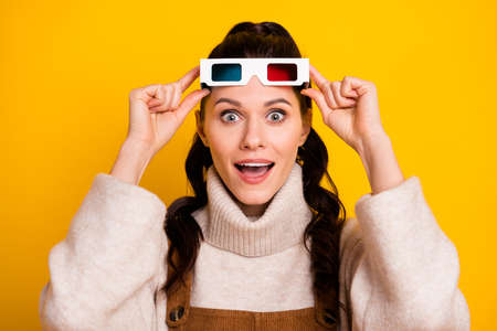 Portrait of attractive amazed cheerful girl wearing 3d spectacles having fun free time isolated over bright yellow color backgroundの写真素材