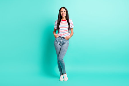 Full size photo of nice brunette optimistic long hairdo lady stand wear t-shirt jeans sneakers isolated on teal color backgroundの写真素材