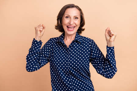 Photo of astonished aged manager brunette lady hands fists wear blue blouse isolated on beige color...