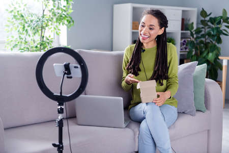 Photo of young happy blogger open box recommend product camera phone indoors inside house homeの写真素材