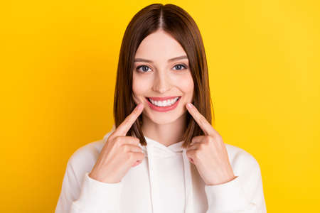 Photo of candid lady direct fingers healthy teeth implants wear white hoodie isolated yellow color...