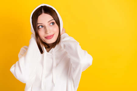 Photo of pretty cozy lady look empty space touch hood wear white sweatshirt isolated yellow color backgroundの写真素材
