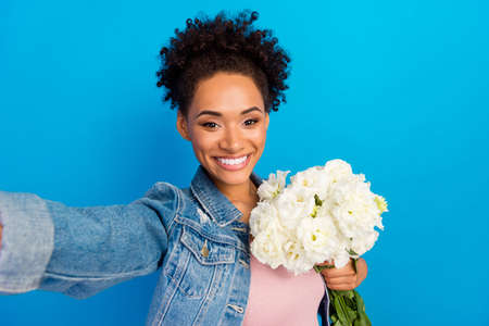 Photo of pretty happy young afro american woman flowers spring make selfie camera isolated on blue color backgroundの写真素材