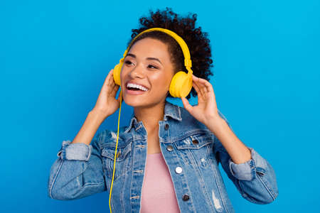 Photo of dreamy cheerful happy young woman wear headphones look empty space isolated on blue color backgroundの写真素材