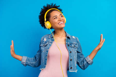Photo of dreamy cool happy young woman wear headphones look empty space isolated on blue color backgroundの写真素材