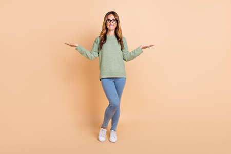 Full length body size view of attractive cheerful wavy-haired woman holding copy space isolated over...