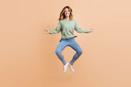 Full length body size photo woman jumping meditating in yoga pose isolated pastel beige color...