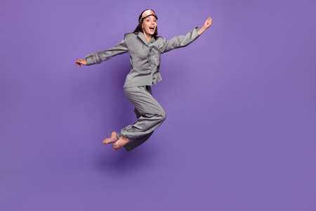 Full length body size view of attractive cheerful woman jumping having fun isolated over violet purple color backgroundの写真素材