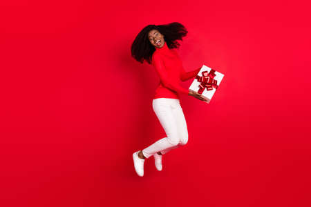 Full body profile side photo of young afro woman happy positive smile hold present jump surprise...