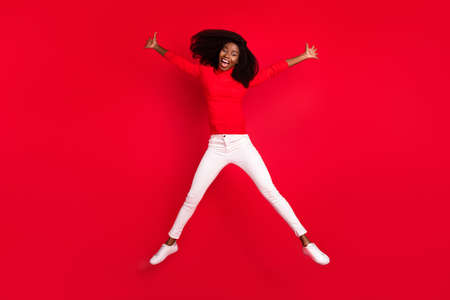 Full size photo of young african woman happy positive smile have fun jump up funky isolated over red color backgroundの写真素材