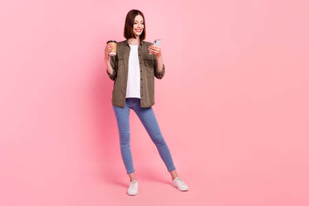 Full body photo of funny brunette hairdo lady look telephone hold coffee wear green shirt jeans...