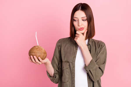 Photo of unsure brunette hairdo young lady drink look cocktail wear khaki shirt isolated on pink color backgroundの写真素材