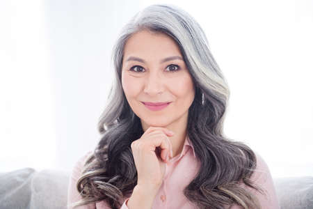 Portrait of attractive cheery calm gray-haired woman staying alone enjoying free time at home house indoorの写真素材