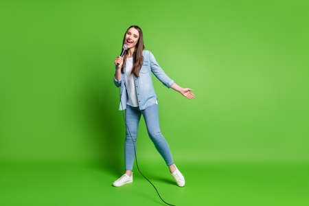 Full length body size view of attractive cheerful girl singing jazz soul having fun isolated over bright green color backgroundの写真素材