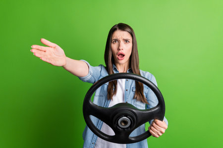 Portrait of attractive mad girl holding in hand steering wheel driving fast isolated over bright green color backgroundの写真素材