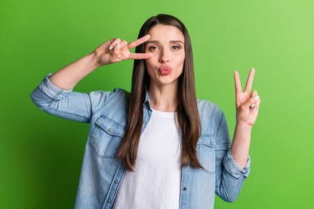 Portrait of attractive amorous funky girl showing double v-sign sending air kiss isolated over...
