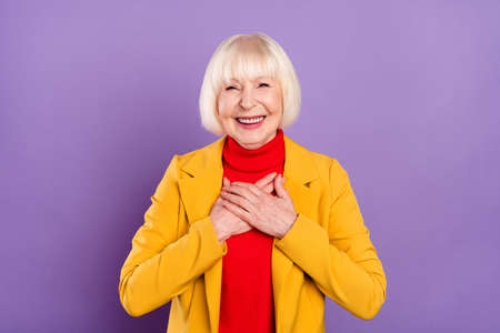Photo of optimistic cute short hairdo aged lady hold hands wear yellow jacket isolated on purple color backgroundの写真素材