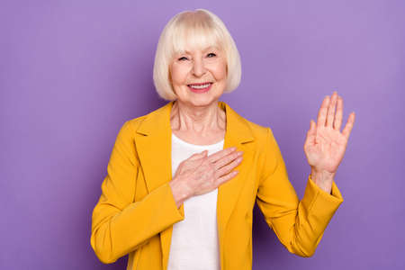 Photo of optimistic pretty short hairdo old lady pray wear yellow jacket isolated on purple color backgroundの写真素材