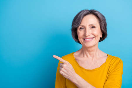 Portrait of attractive cheerful woman demonstrating copy empty blank space ad decision isolated over vivid blue color backgroundの写真素材