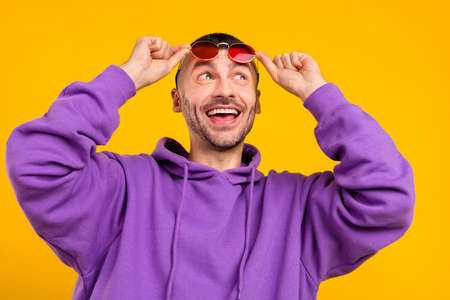 Portrait of attractive cheerful dreamy guy touching specs good mood vacation isolated over vibrant...
