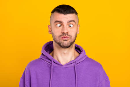 Portrait of attractive funny humorous crazy guy fooling grimacing isolated over bright yellow color...