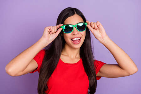 Photo of shiny excited woman dressed red t-shirt arms dark spectacles smiling isolated purple color...