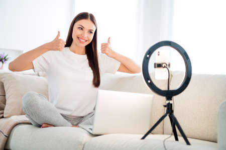 Portrait of attractive cheerful girl giving web lesson seminar training showing thumbup at light...