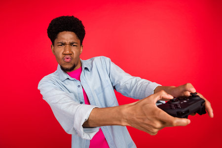 Photo of young black guy addicted play game competition console joystick weekend isolated over red...