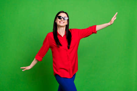 Photo of sweet brunette millennial lady dance wear eyewear red shirt isolated on green color backgroundの写真素材