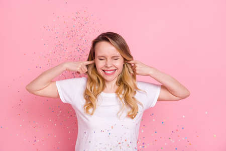 Photo portrait woman in white t-shirt closed ears at party with flying confetti isolated pastel pink...