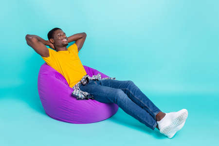 Profile full body photo of cheerful brunette hairdo millennial man sleep wear yellow t-shirt jeans sneakers isolated on cyan color backgroundの写真素材