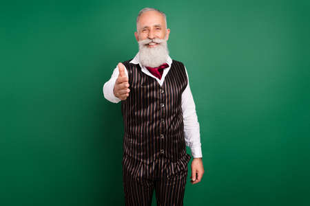Photo of positive nice mature employer man invite you handshake wear striped waistcoat on green color backgroundの写真素材