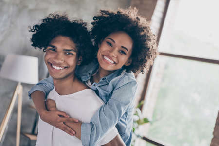 Photo of happy positive afro american couple good mood piggyback ride smile indoors inside house...