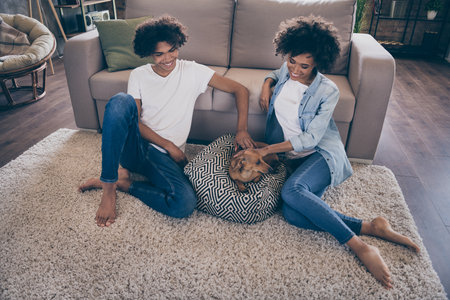 Full length photo of young cheerful african couple happy positive smile sit floor companion dog indoorsの写真素材