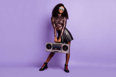 Photo of young girl hold boom box wear vintage glasses glossy shirt mini skirt isolated violet color backgroundの写真素材