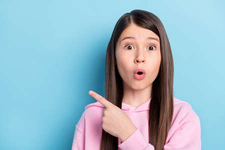 Portrait of beautiful trendy amazed stunned girl showing copy space idea isolated over bright blue color backgroundの写真素材