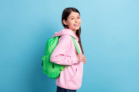 Profile side photo of young preteen girl happy positive smile pupil wear backpack isolated over blue...