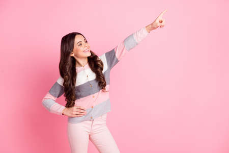 Photo of happy charming little girl point finger empty space look good mood isolated on pink color backgroundの写真素材