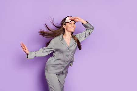 Photo portrait of girl in grey pajama sleeping mask smiling looking far empty space isolated pastel...